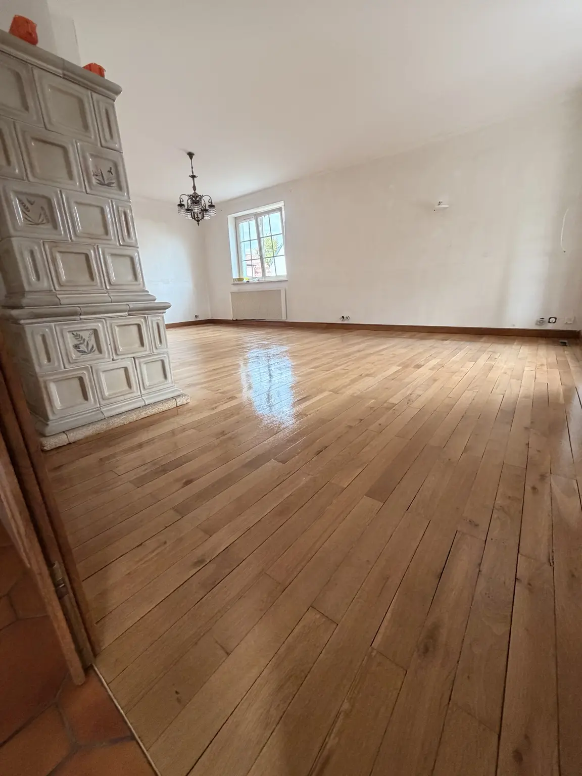 Parquet rénové autour d’un poêle en faïence à Ottmarsheim près de Mulhouse