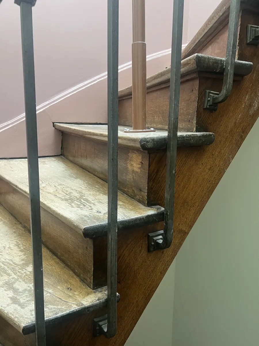 Détail d’un escalier en bois avec ancienne finition sombre et zones d’usure avant ponçage
