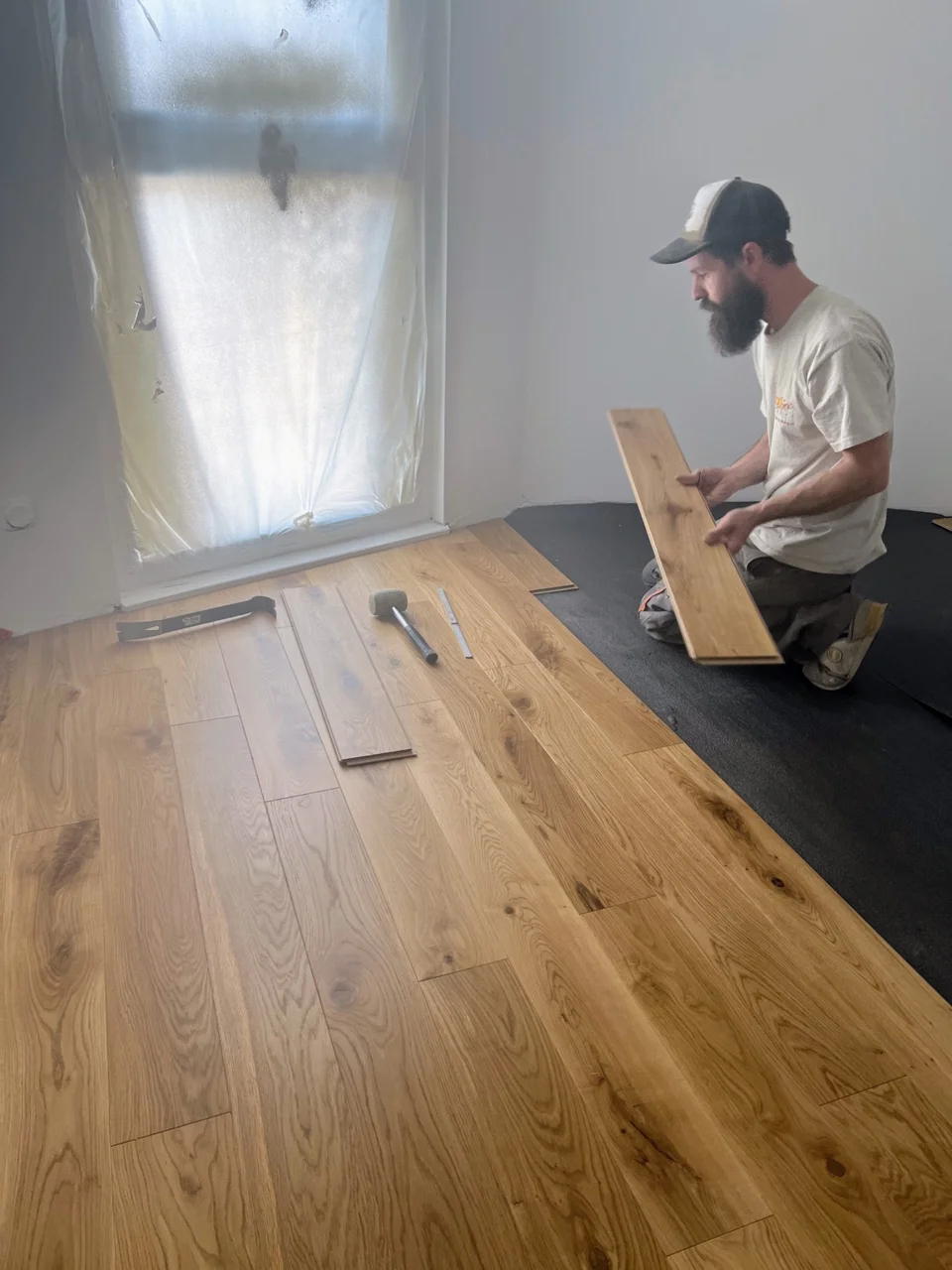 Artisan ajustant une lame sur une sous-couche pendant la pose du parquet